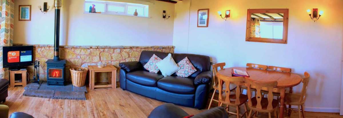Cinders cottage living area with wooden flooring and wood burning stove