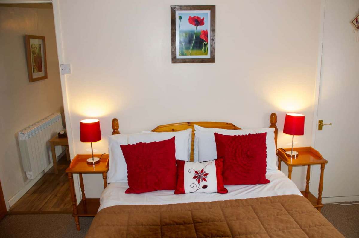 Lake cottage double bedroom with red cushions and lampshades